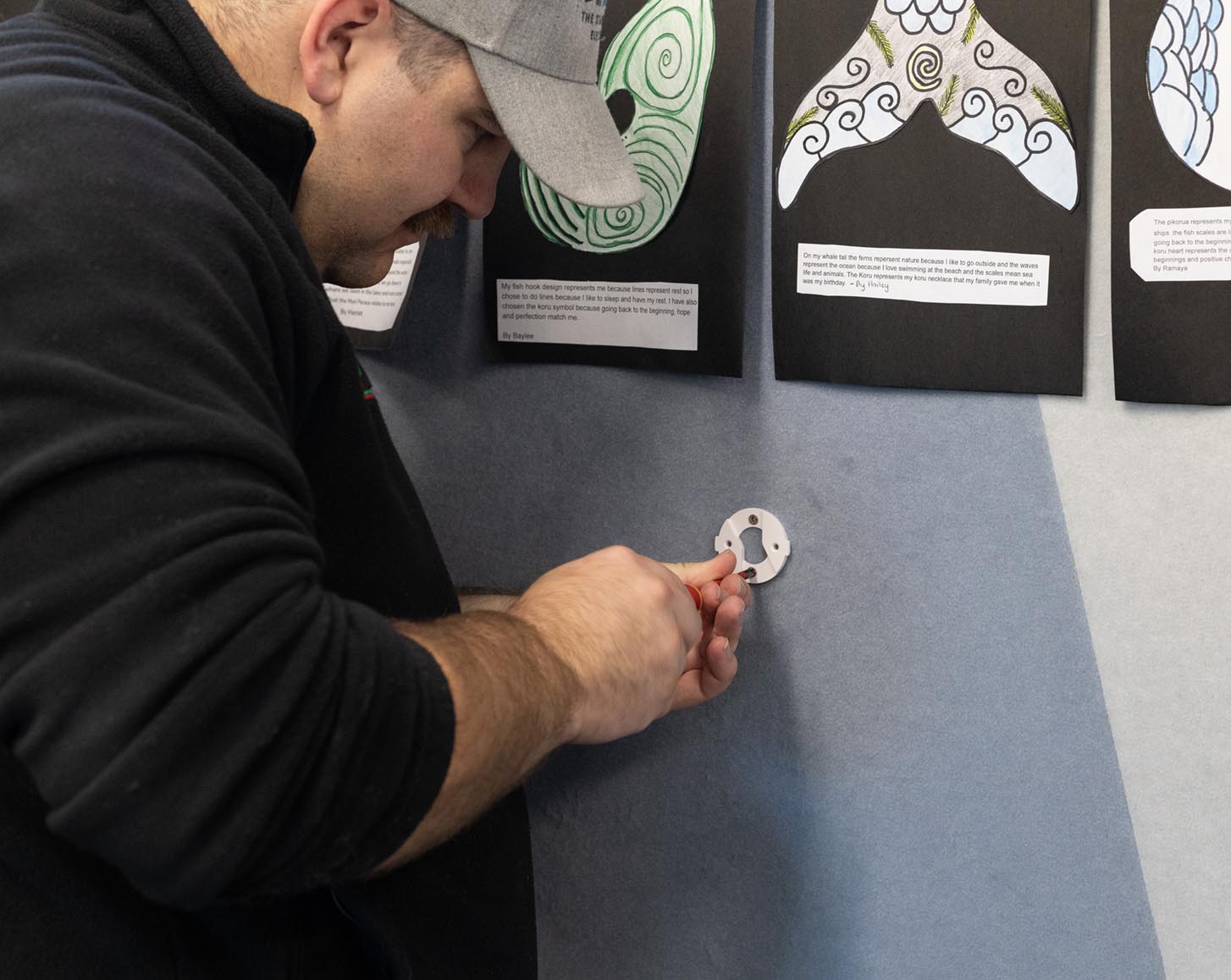 An installer screws an AirSuite mounting bracket into the wall in a classroom