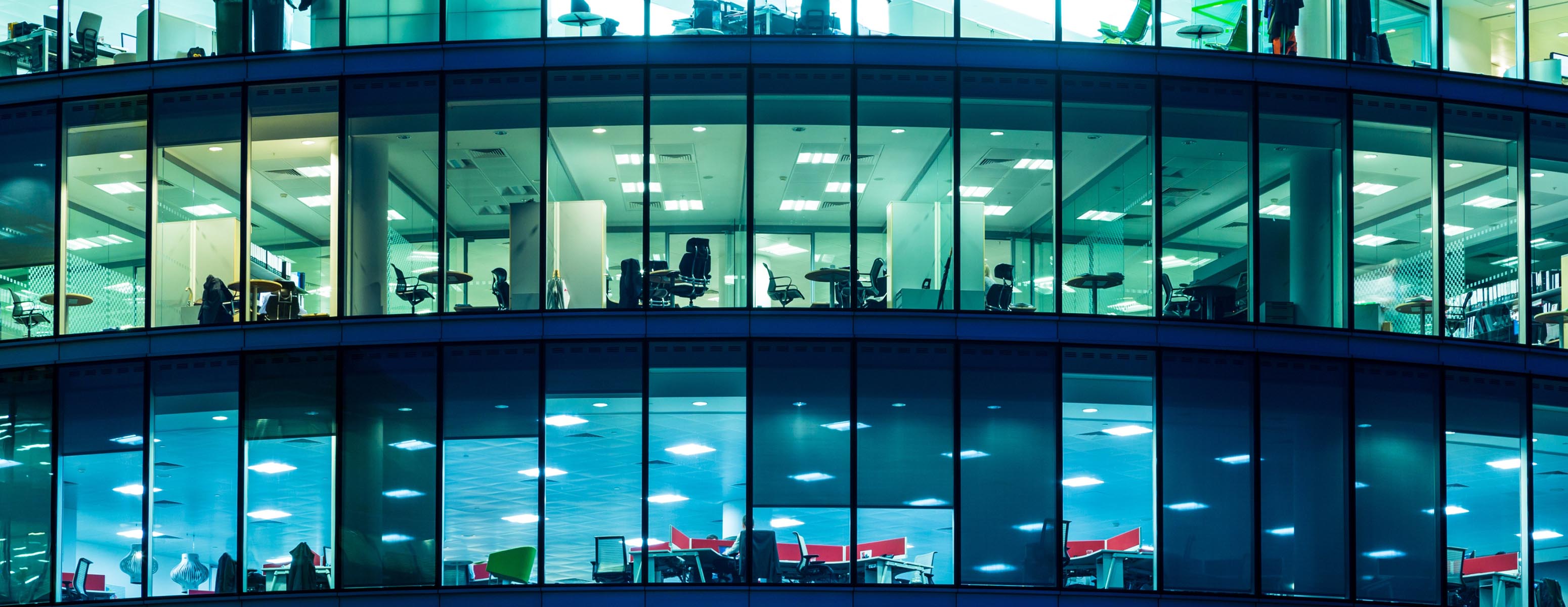 Looking into a high-rise building at night time, with the lights turned on on each floor