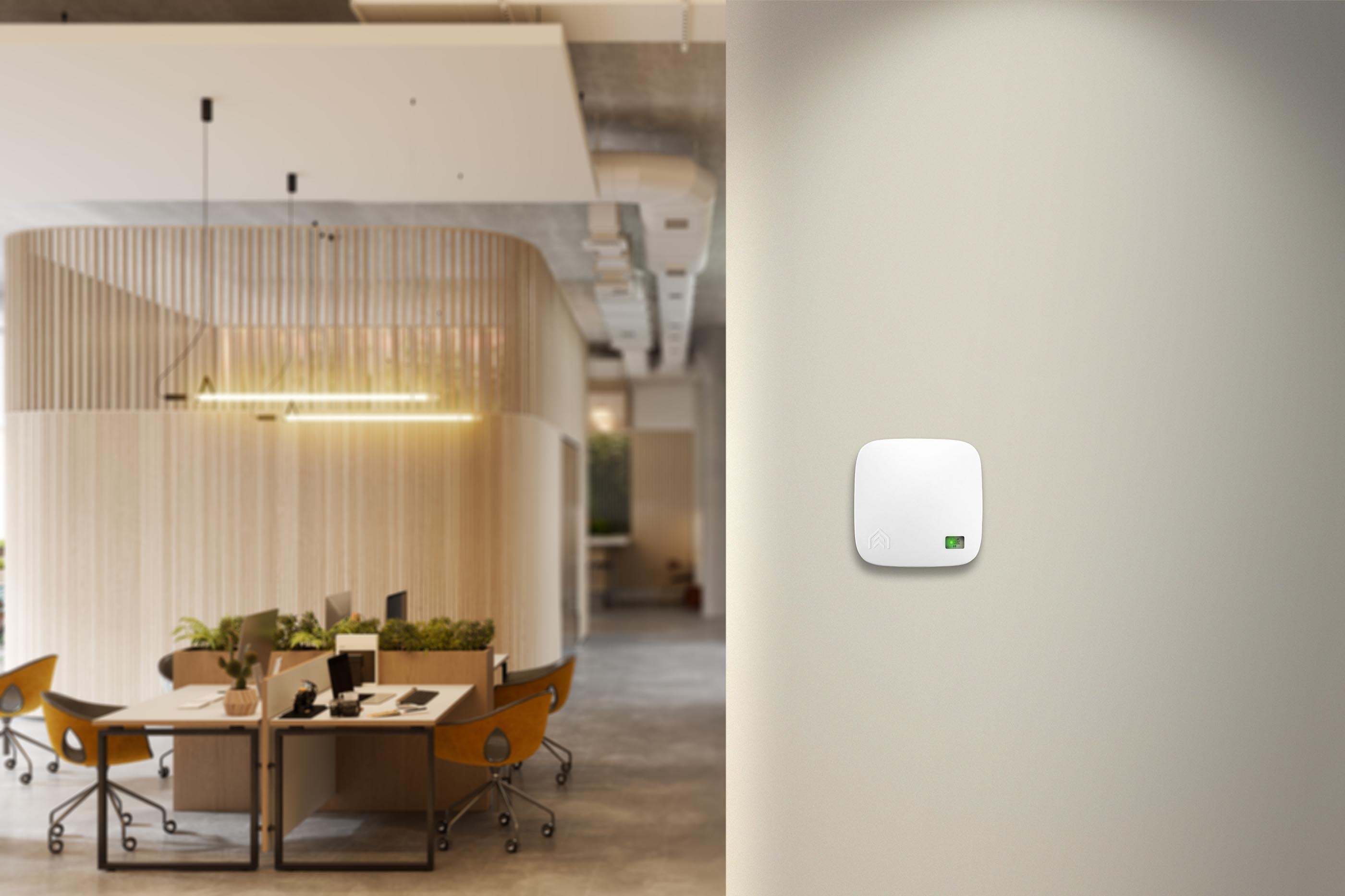 An AirSuite sensor on a wall, with office desks in the background