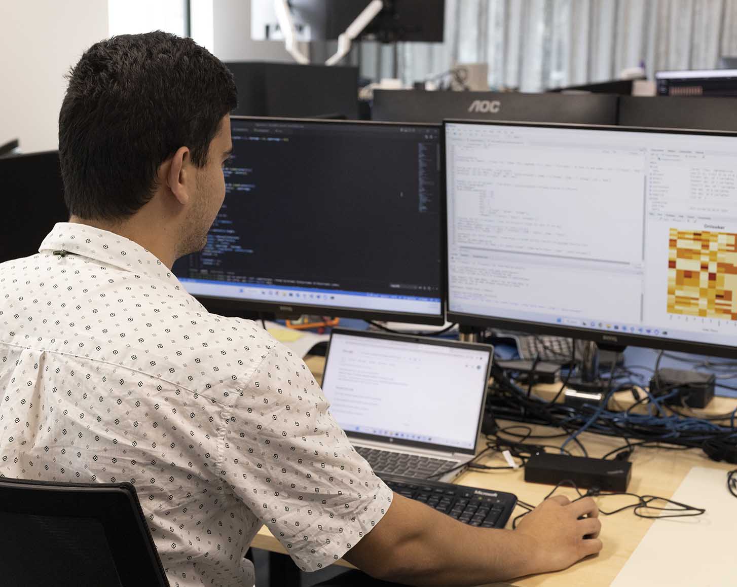 Matthew looks at data on two computer screens