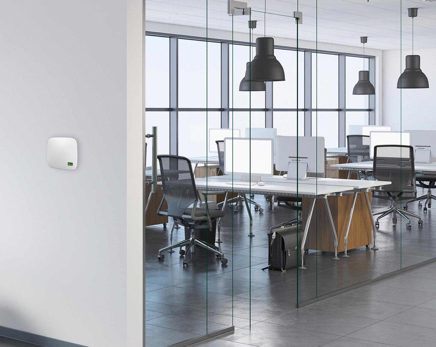 An AirSuite sensor on a wall, with office desks in the background